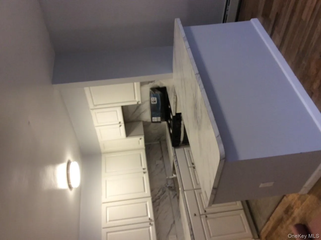 Kitchen featuring light countertops, white cabinets, black range, dark wood-style flooring, and decorative backsplash Kitchen featuring light countertops, white cabinets, black range, dark wood-style flooring, and decorative backsplash