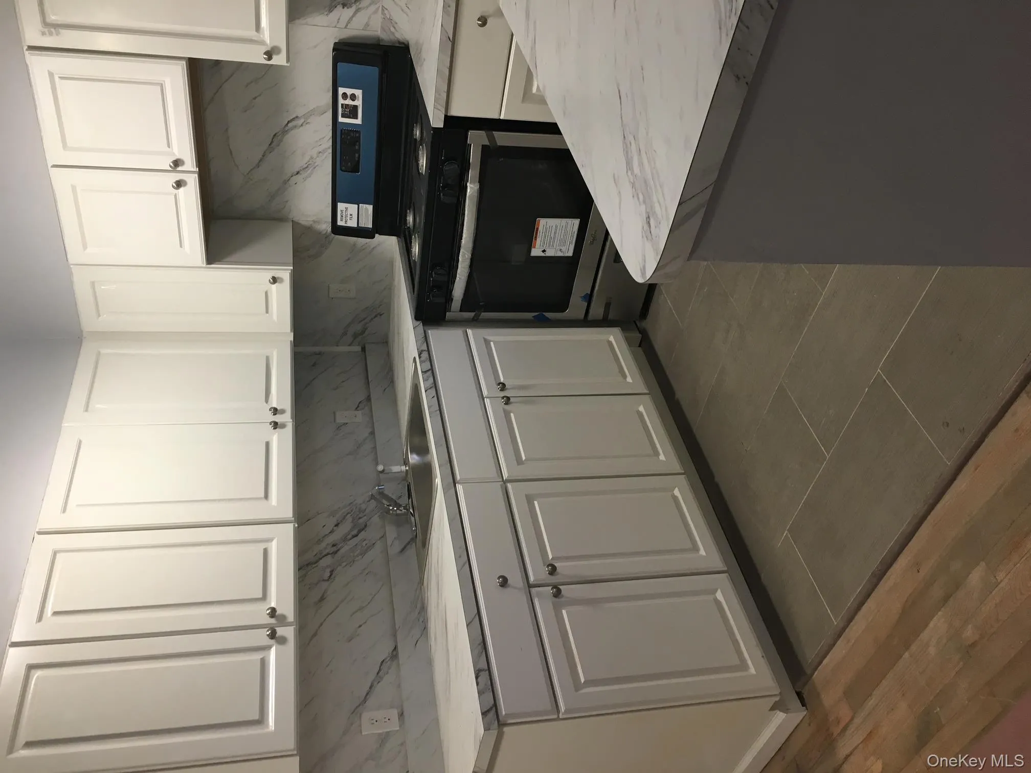 Kitchen with stove, white cabinetry, light countertops, and backsplash Kitchen with stove, white cabinetry, light countertops, and backsplash