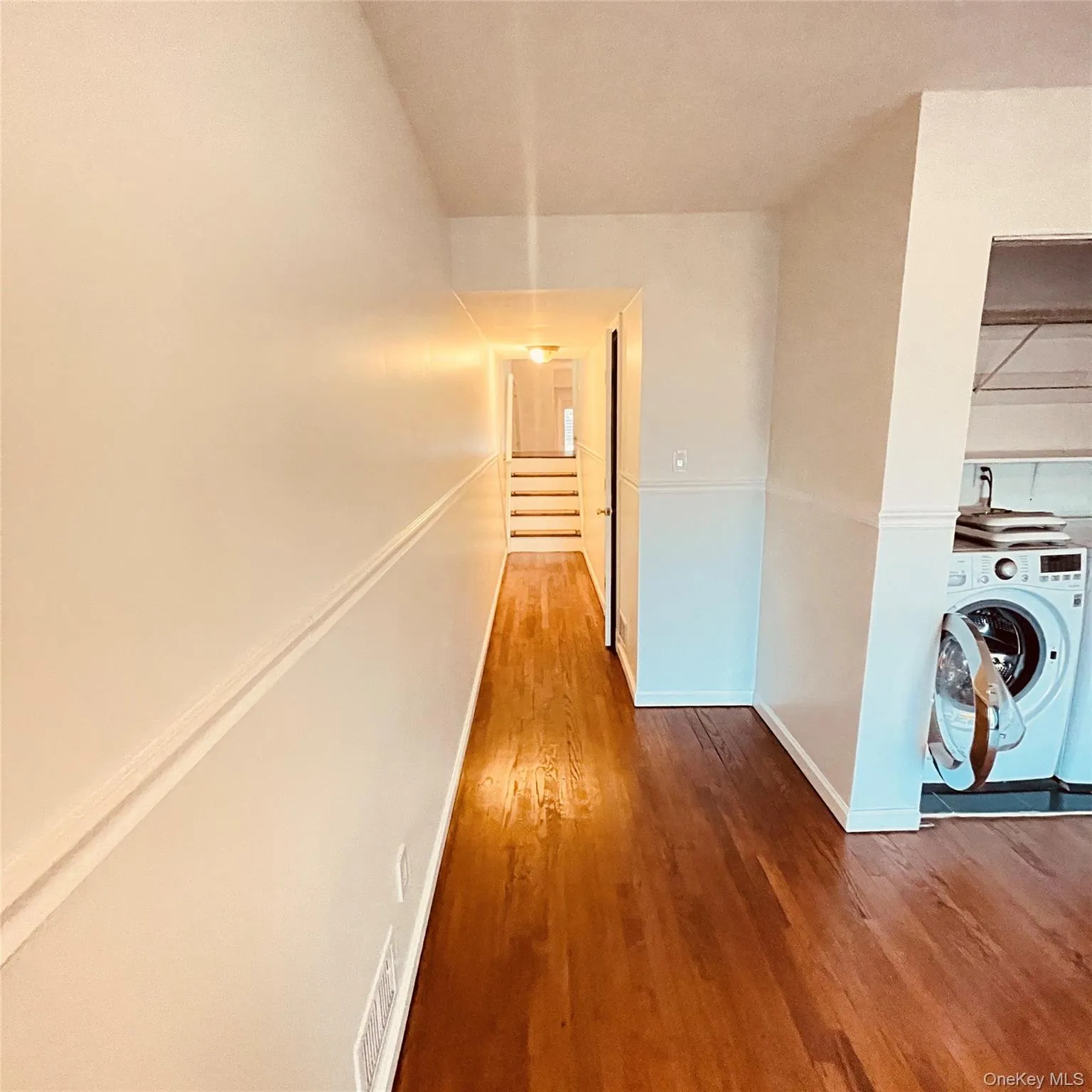 Corridor featuring washer / clothes dryer and wood finished floors Corridor featuring washer / clothes dryer and wood finished floors