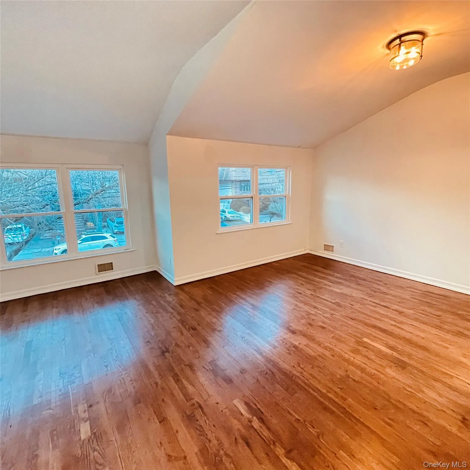 Unfurnished room featuring lofted ceiling and wood-type flooring Unfurnished room featuring lofted ceiling and wood-type flooring