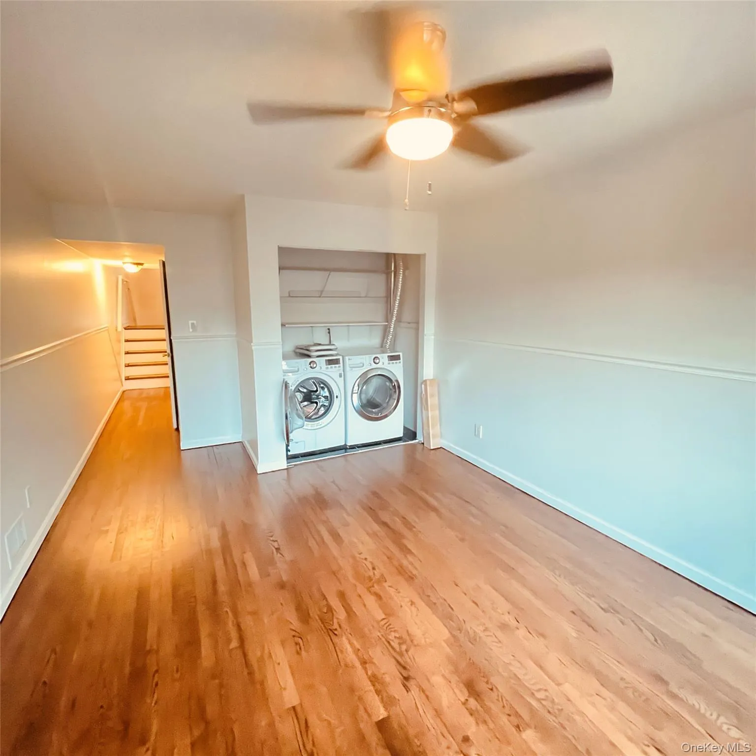 Laundry area with light wood-type flooring, washer and dryer, and a ceiling fan Laundry area with light wood-type flooring, washer and dryer, and a ceiling fan