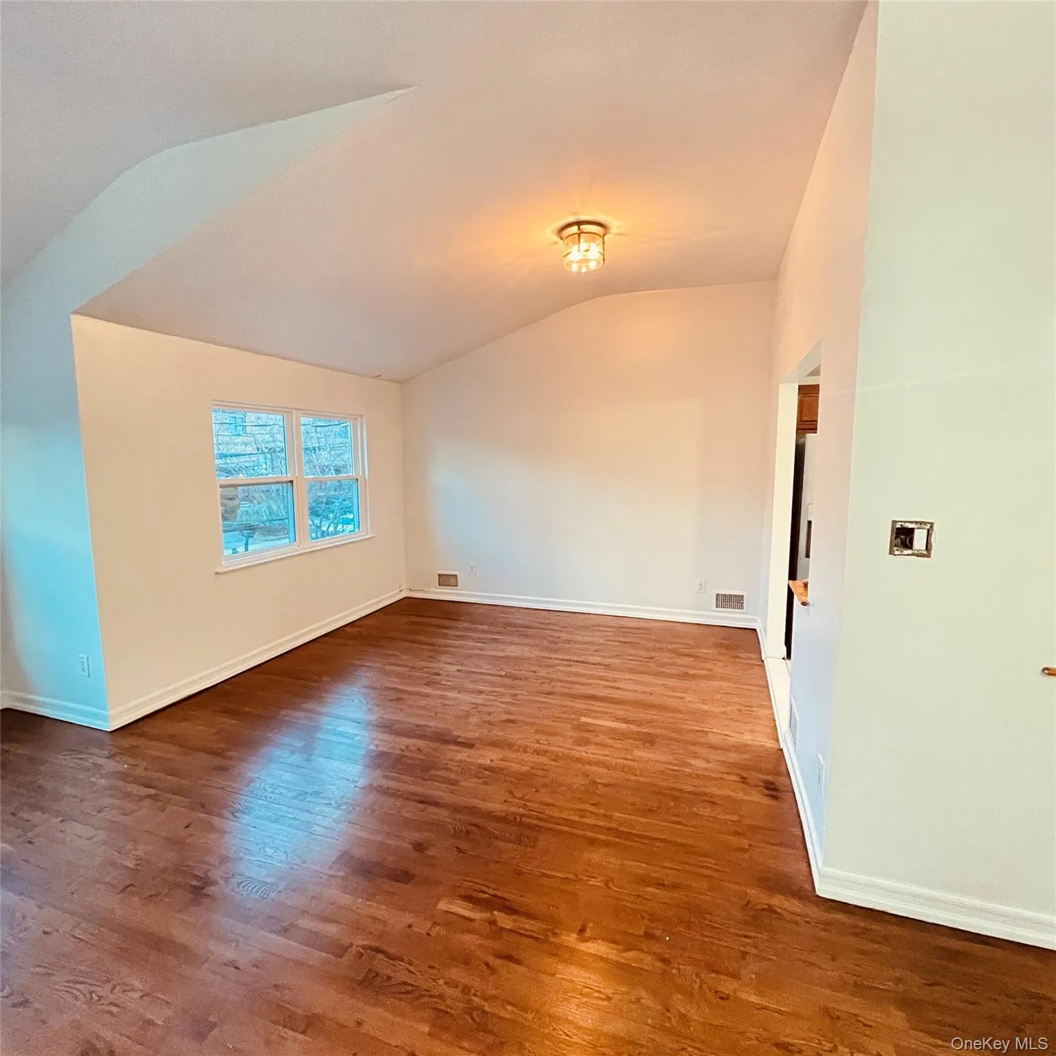 Unfurnished room with lofted ceiling and dark wood-style floors Unfurnished room with lofted ceiling and dark wood-style floors