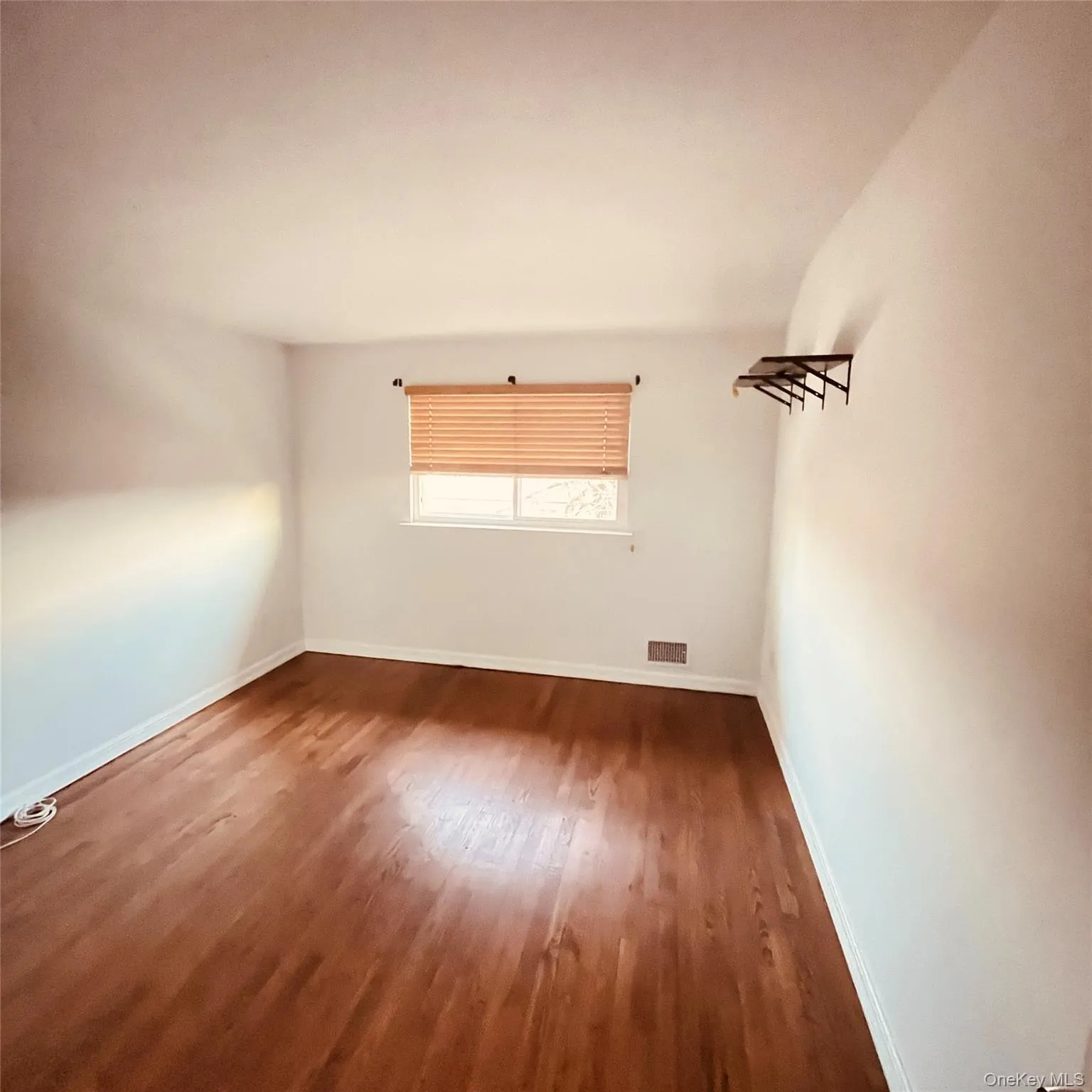 Empty room featuring wood finished floors and baseboards Empty room featuring wood finished floors and baseboards