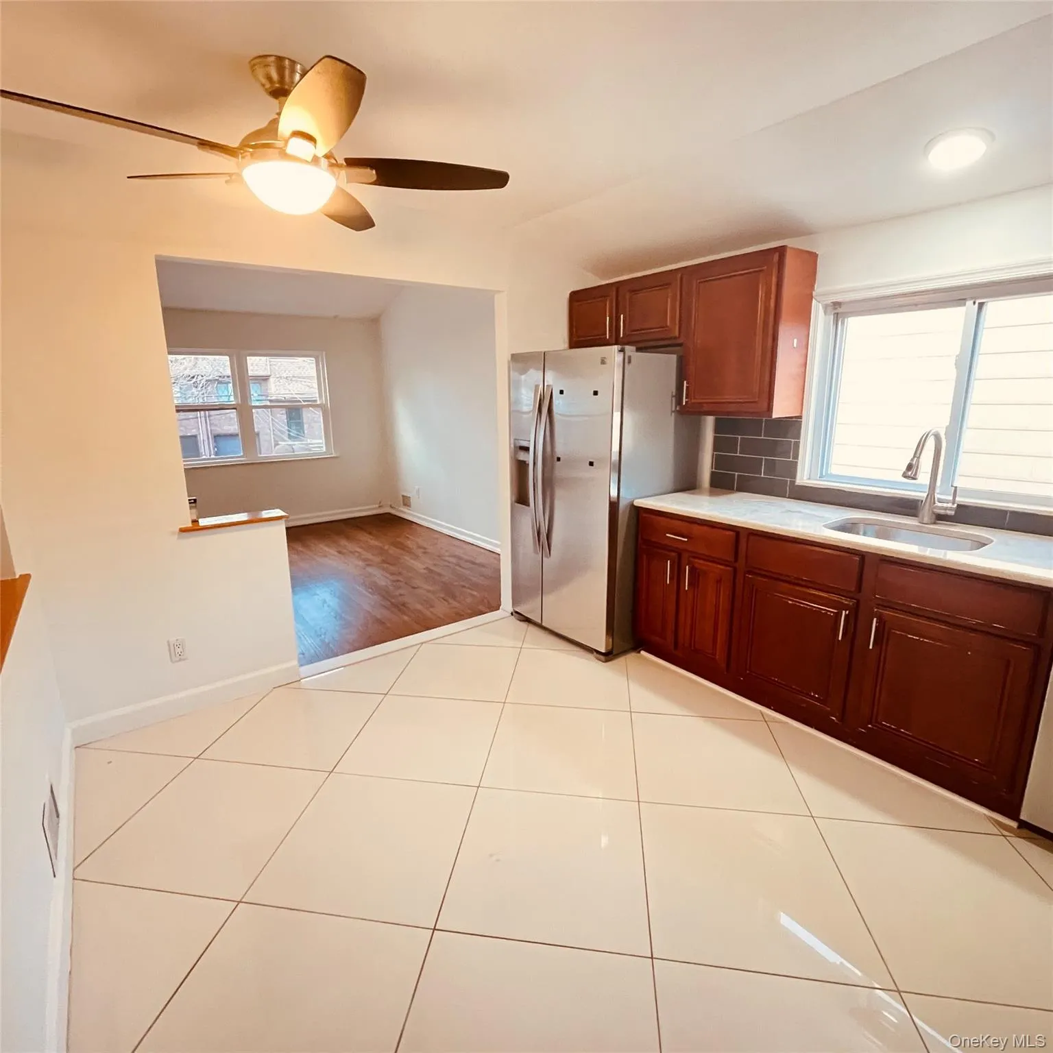 Kitchen with tasteful backsplash, stainless steel fridge with ice dispenser, a ceiling fan, and healthy amount of natural light Kitchen with tasteful backsplash, stainless steel fridge with ice dispenser, a ceiling fan, and healthy amount of natural light