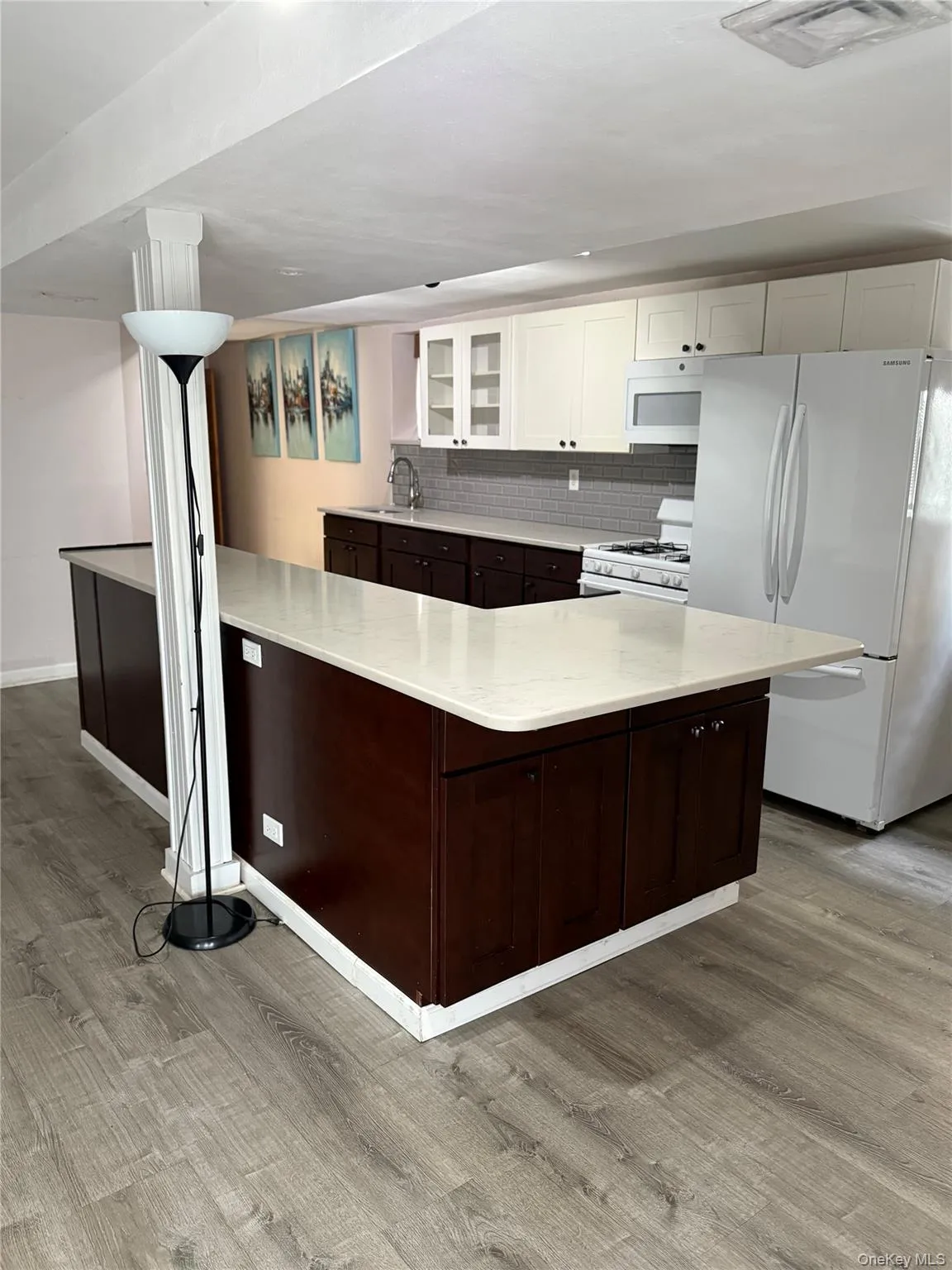 Kitchen featuring white appliances, white cabinetry, glass insert cabinets, backsplash, and light stone countertops Kitchen featuring white appliances, white cabinetry, glass insert cabinets, backsplash, and light stone countertops