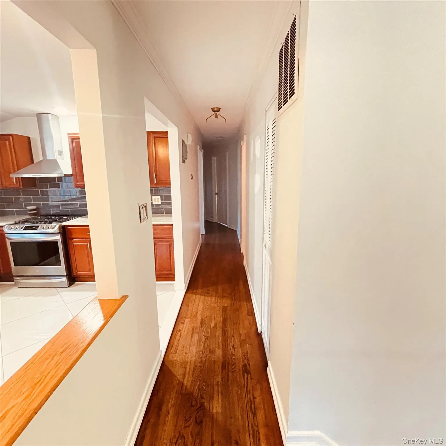 Corridor featuring light wood-style floors and ornamental molding Corridor featuring light wood-style floors and ornamental molding