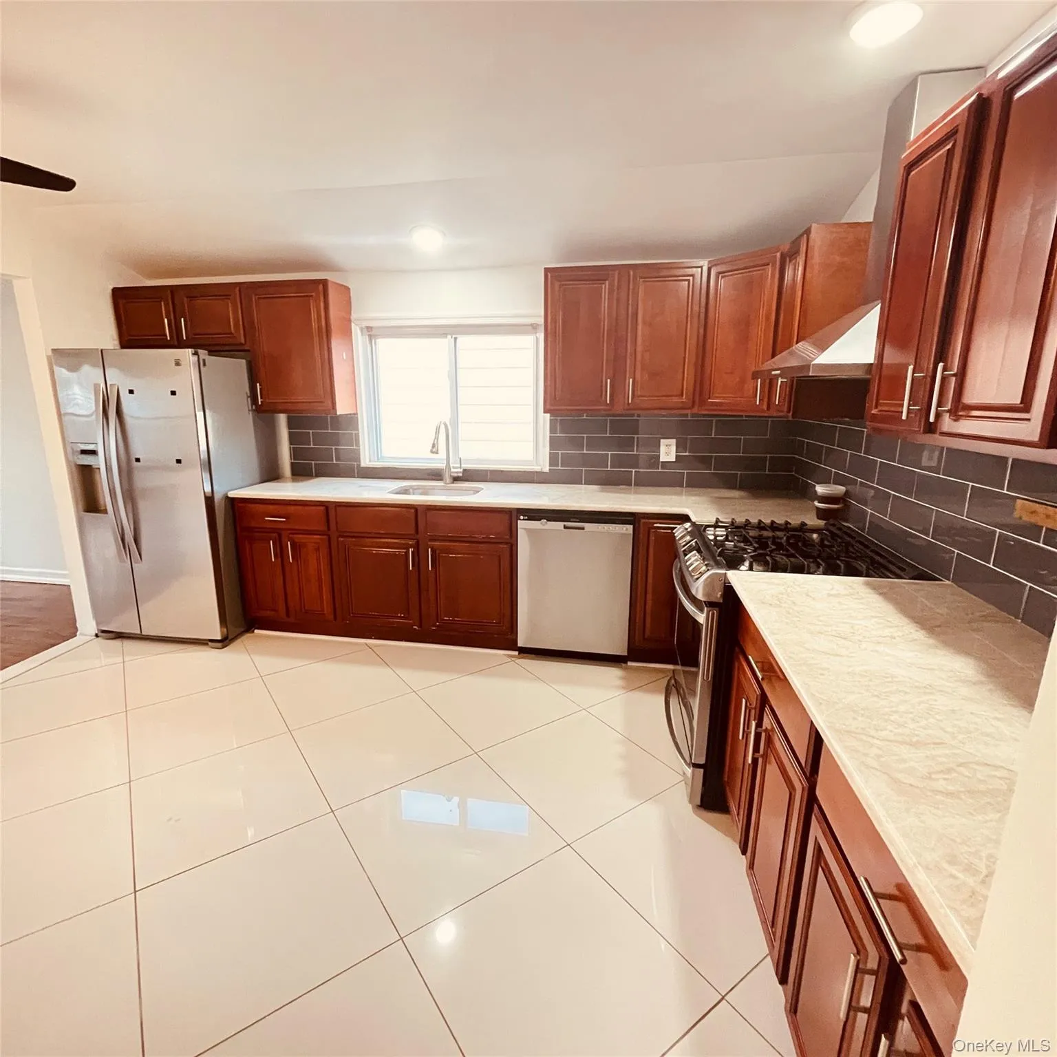 Kitchen featuring stainless steel appliances, tasteful backsplash, under cabinet range hood, brown cabinetry, and recessed lighting Kitchen featuring stainless steel appliances, tasteful backsplash, under cabinet range hood, brown cabinetry, and recessed lighting