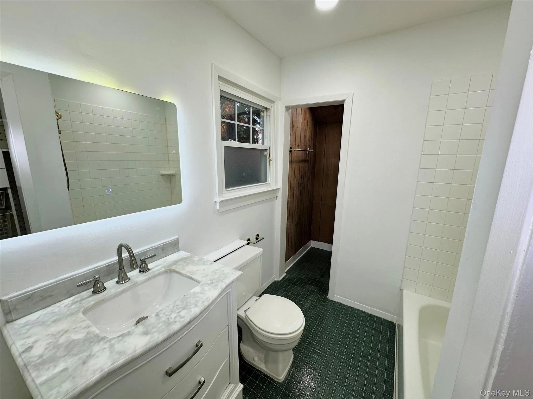 Bathroom with vanity, dark tile patterned flooring, and bathtub / shower combination Bathroom with vanity, dark tile patterned flooring, and bathtub / shower combination