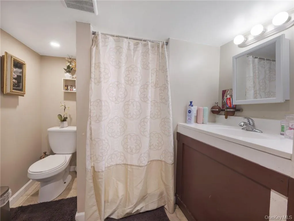 Full bath with vanity, a shower with shower curtain, and light tile patterned floors Full bath with vanity, a shower with shower curtain, and light tile patterned floors
