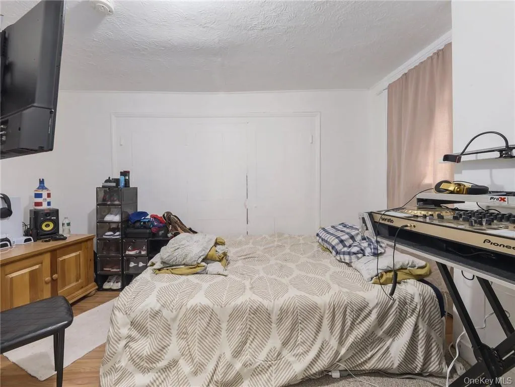 Bedroom with light wood finished floors and a textured ceiling Bedroom with light wood finished floors and a textured ceiling