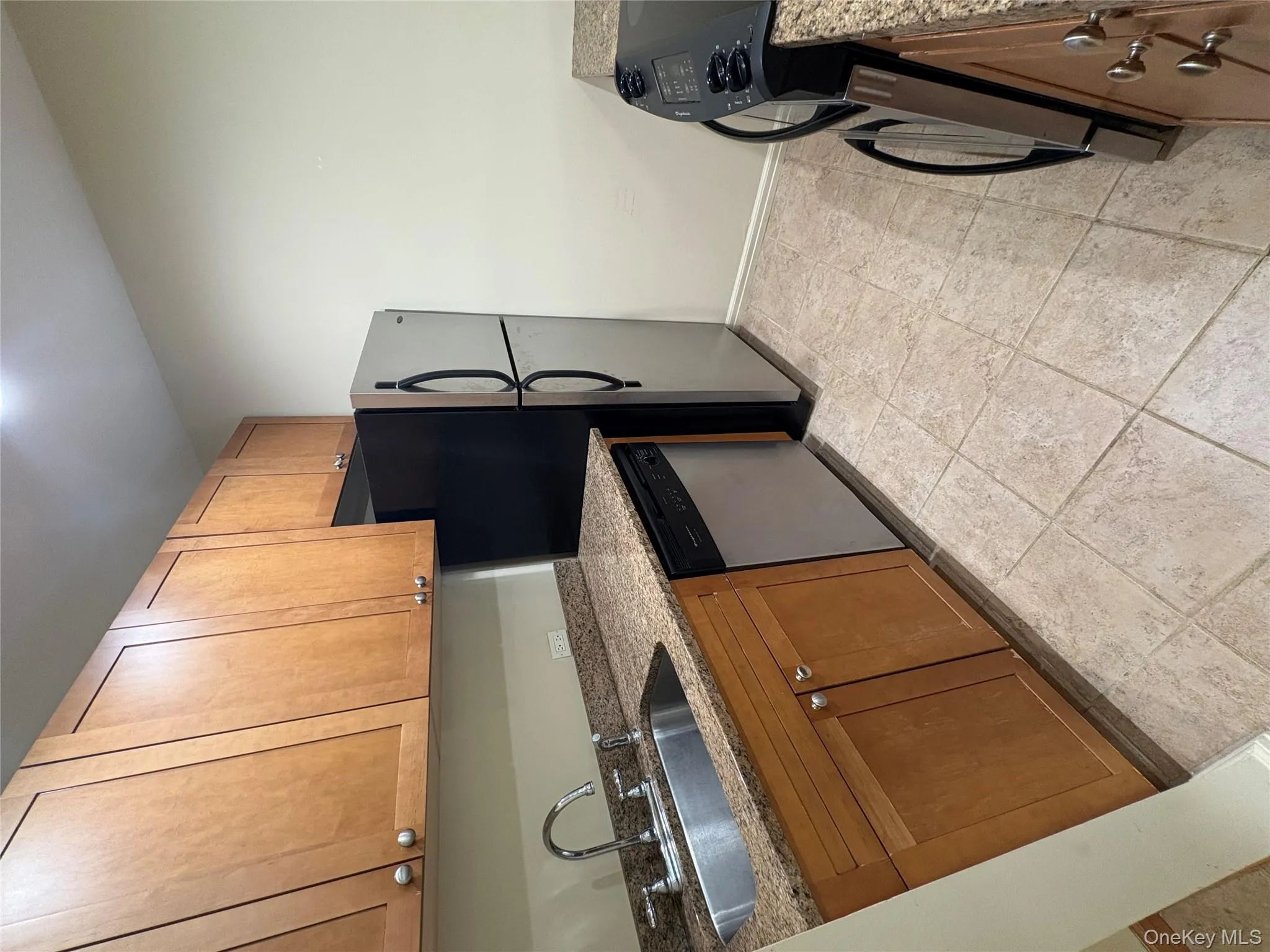 Kitchen featuring dark stone counters, brown cabinetry, stove, and dishwasher Kitchen featuring dark stone counters, brown cabinetry, stove, and dishwasher