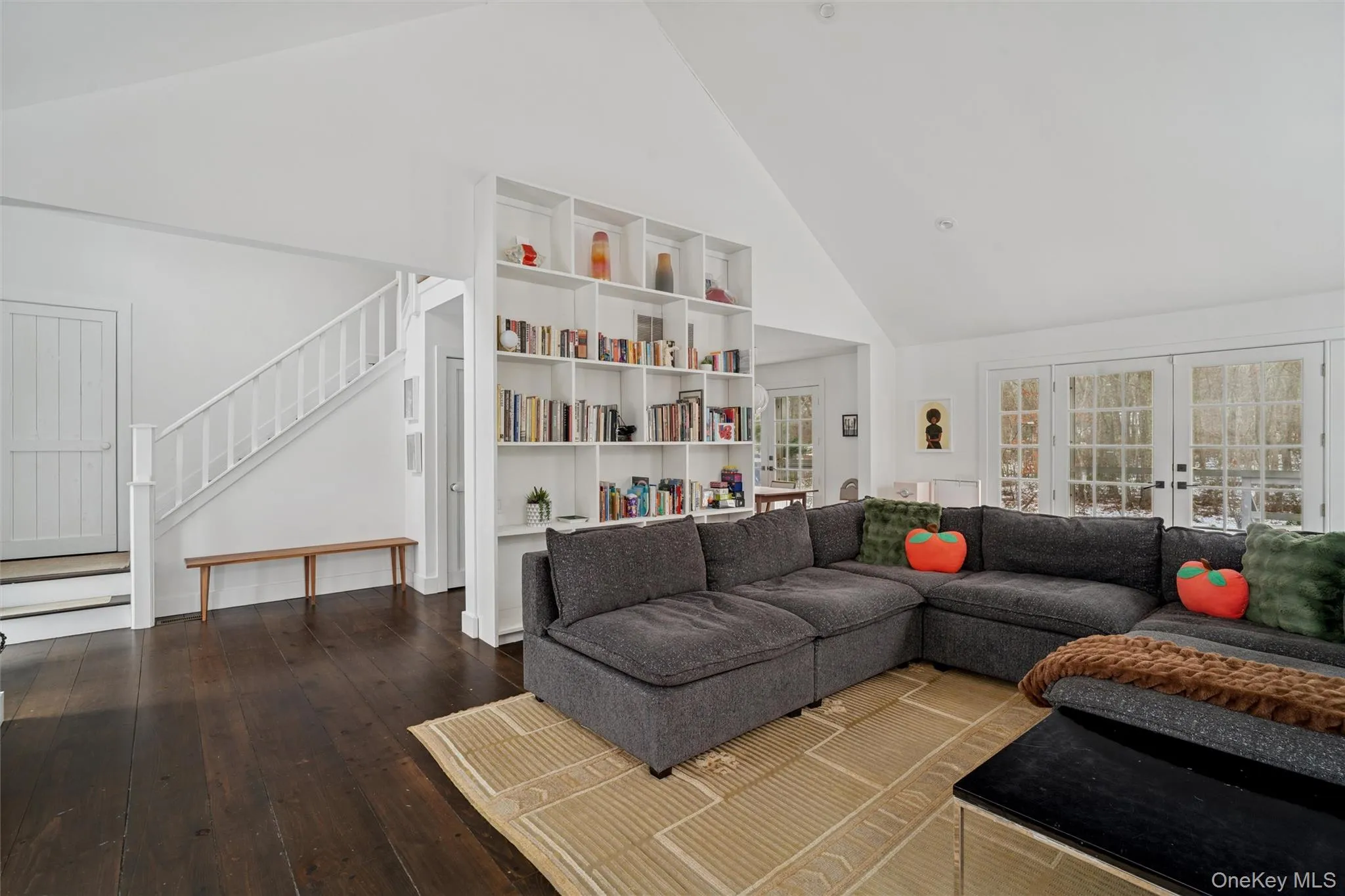 Living area with high vaulted ceiling, french doors, wood-type flooring, and stairway Living area with high vaulted ceiling, french doors, wood-type flooring, and stairway