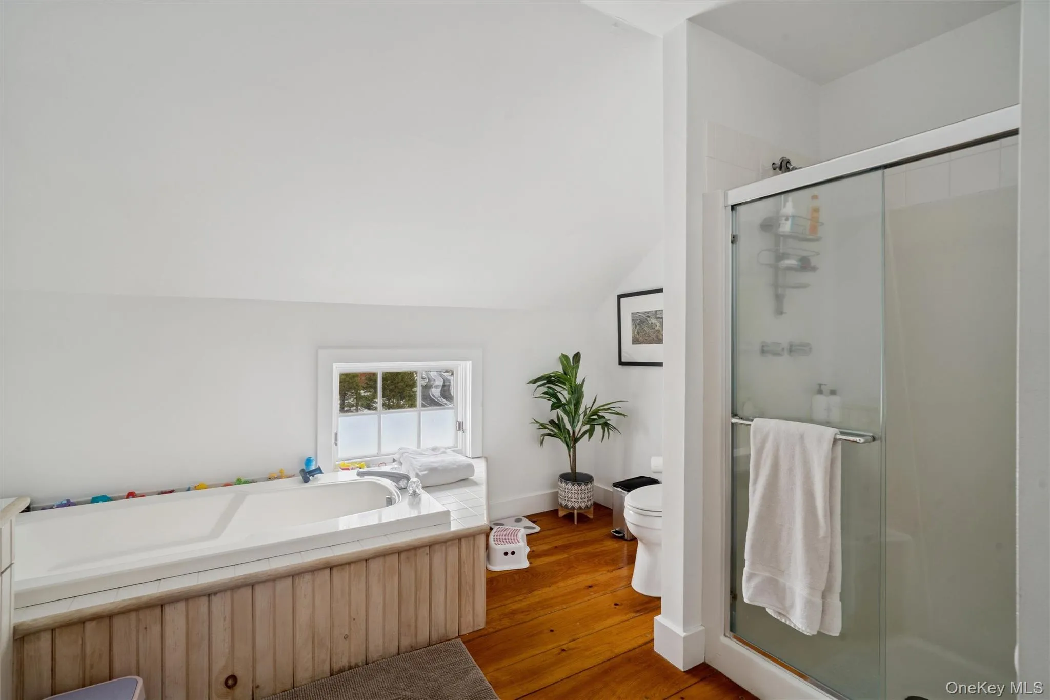 Bathroom featuring a stall shower, hardwood / wood-style flooring, a bath, and lofted ceiling Bathroom featuring a stall shower, hardwood / wood-style flooring, a bath, and lofted ceiling