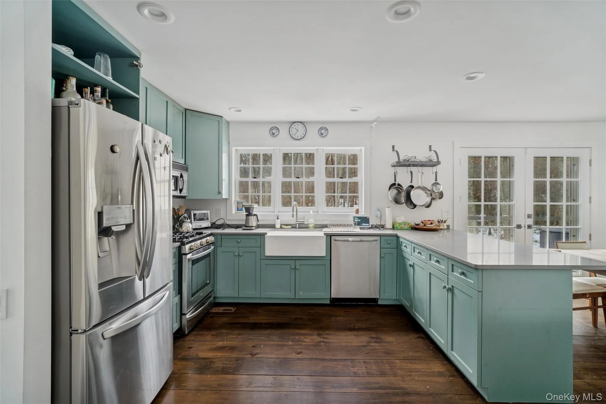 Kitchen featuring green cabinets, stainless steel appliances, a peninsula, french doors, and dark wood-style flooring Kitchen featuring green cabinets, stainless steel appliances, a peninsula, french doors, and dark wood-style flooring