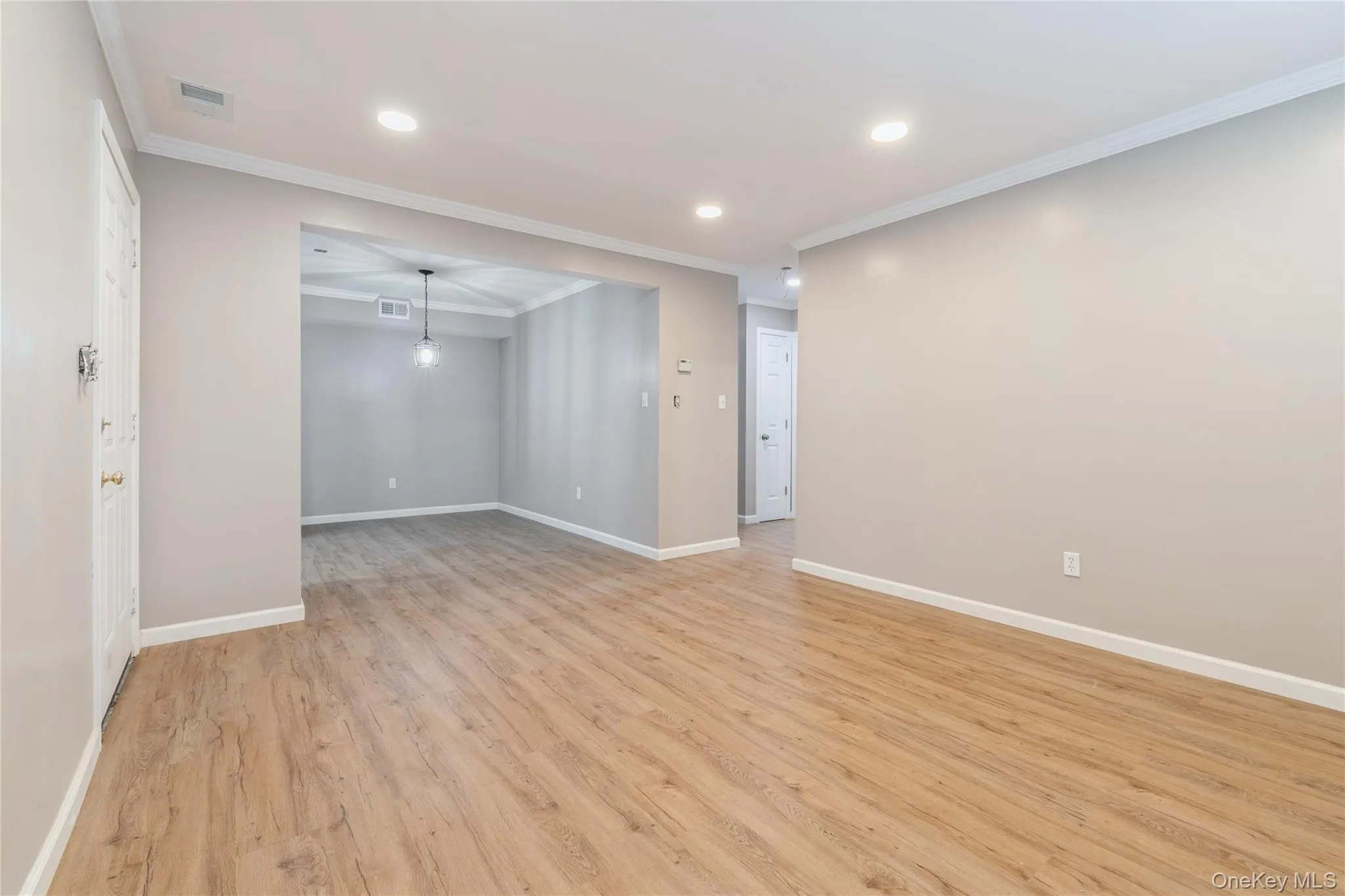 Empty room with crown molding, light wood-style flooring, and recessed lighting Empty room with crown molding, light wood-style flooring, and recessed lighting