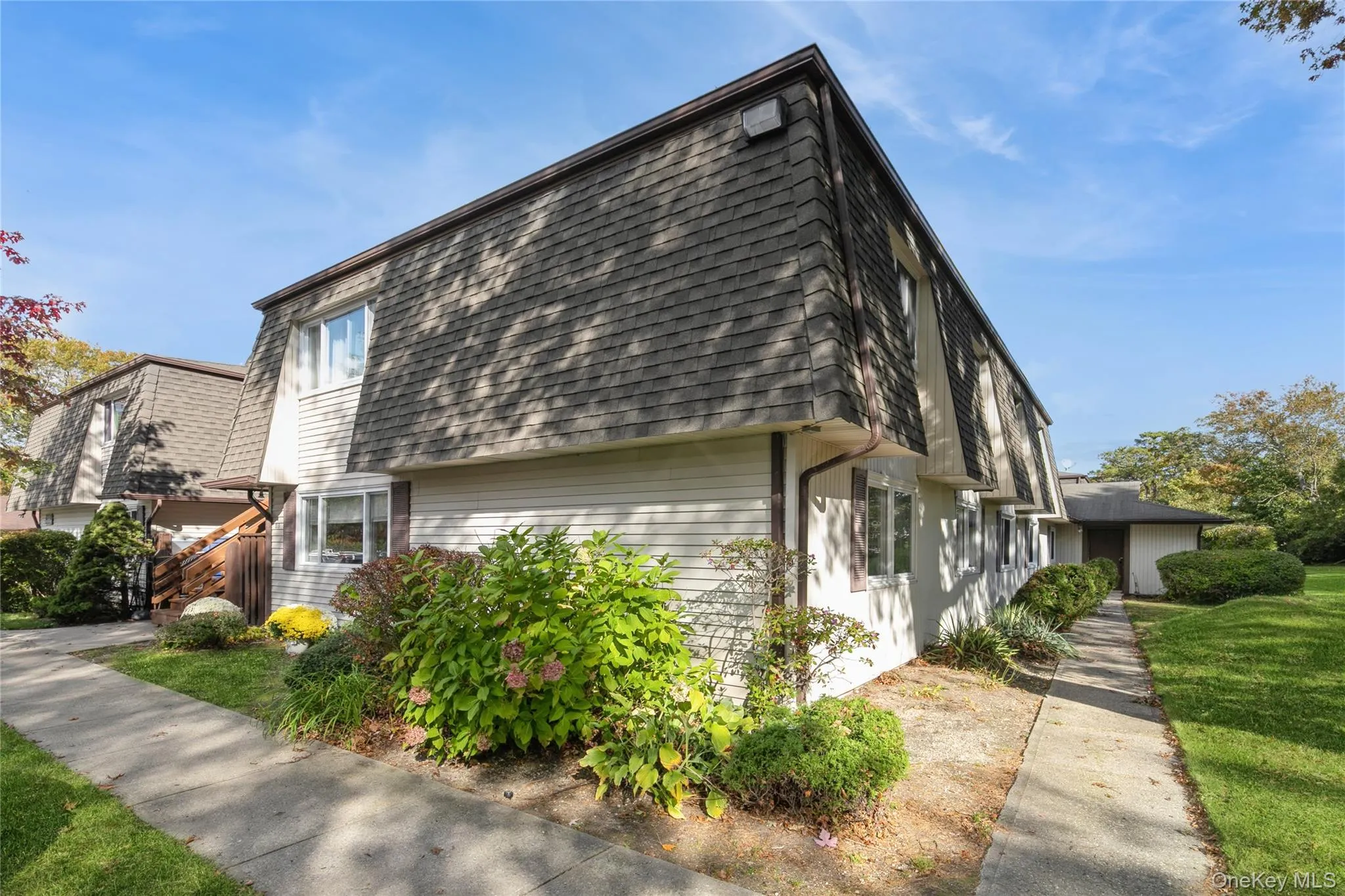 View of side of property featuring mansard roof, a lawn, and roof with shingles View of side of property featuring mansard roof, a lawn, and roof with shingles