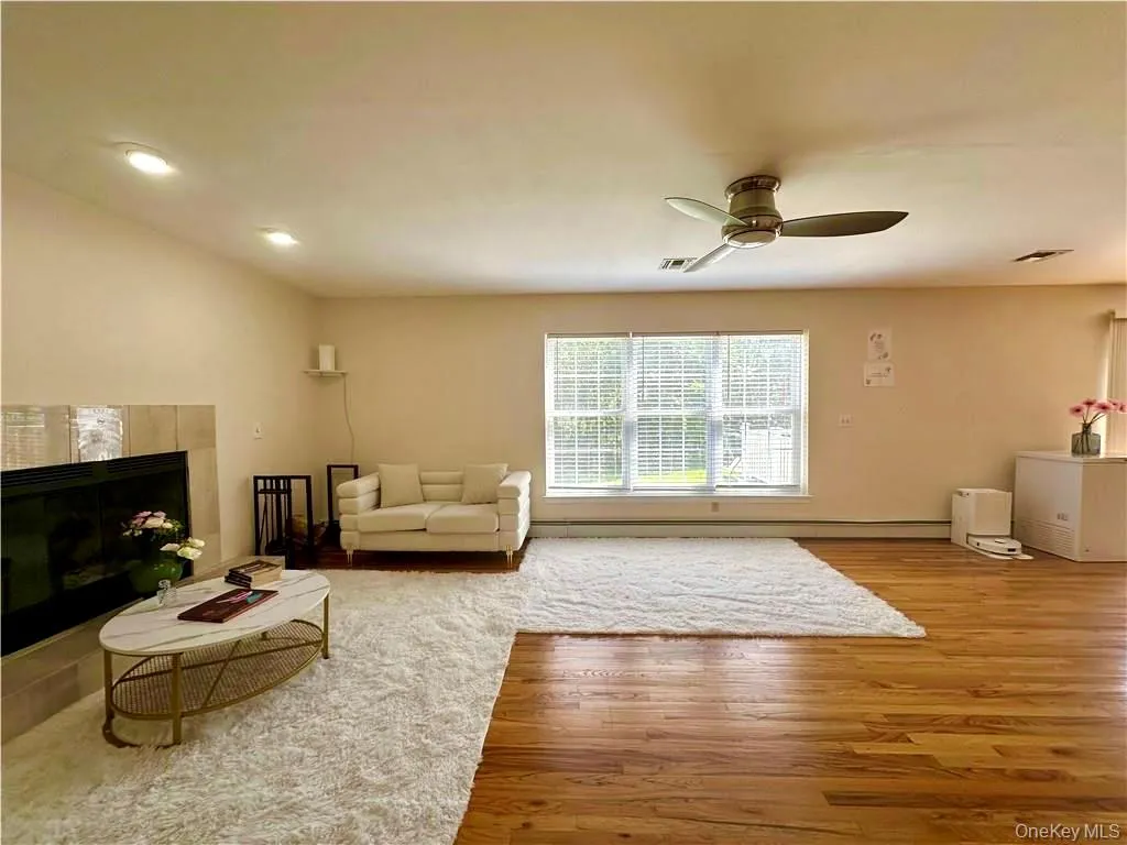 Living area with a fireplace, light wood-type flooring, ceiling fan, and recessed lighting Living area with a fireplace, light wood-type flooring, ceiling fan, and recessed lighting