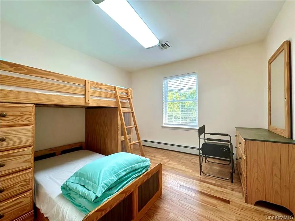 Bedroom featuring light wood finished floors and baseboard heating Bedroom featuring light wood finished floors and baseboard heating