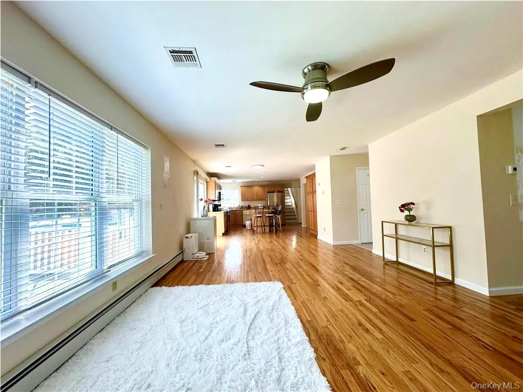 Living room featuring a baseboard heating unit, light wood-type flooring, and ceiling fan Living room featuring a baseboard heating unit, light wood-type flooring, and ceiling fan