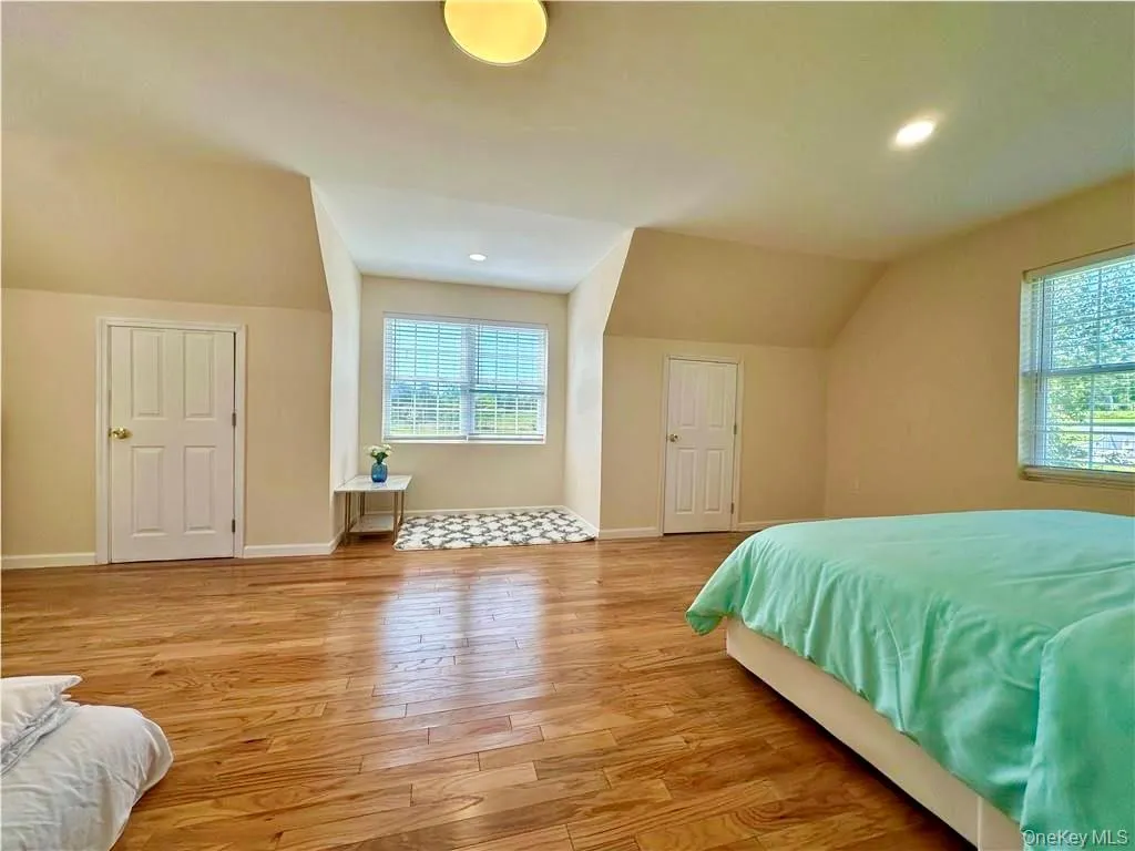 Bedroom with light wood-style floors, recessed lighting, and vaulted ceiling Bedroom with light wood-style floors, recessed lighting, and vaulted ceiling
