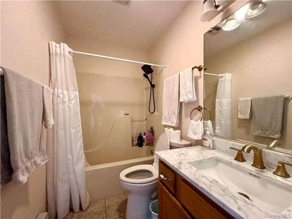 Bathroom featuring shower / bath combo, vanity, and light tile patterned floors Bathroom featuring shower / bath combo, vanity, and light tile patterned floors
