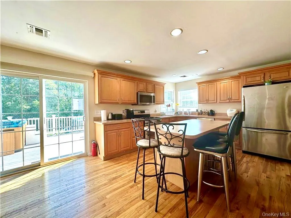 Kitchen with appliances with stainless steel finishes, a center island, a breakfast bar area, recessed lighting, and light wood-style floors Kitchen with appliances with stainless steel finishes, a center island, a breakfast bar area, recessed lighting, and light wood-style floors
