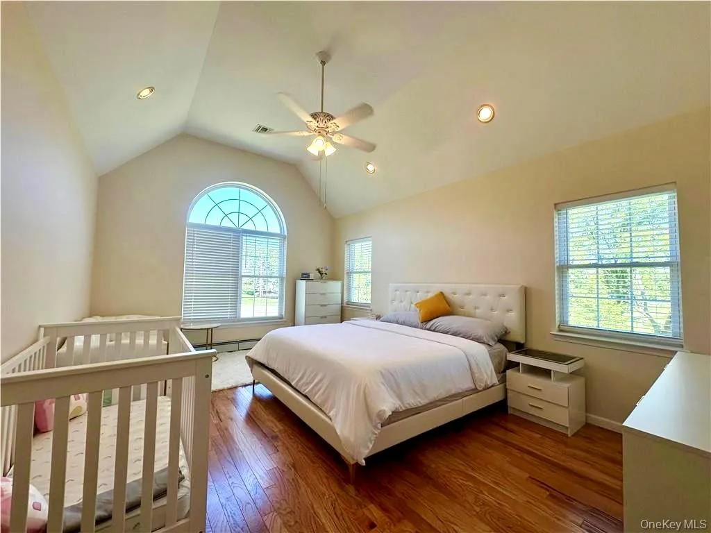 Bedroom with vaulted ceiling, wood-type flooring, a ceiling fan, and recessed lighting Bedroom with vaulted ceiling, wood-type flooring, a ceiling fan, and recessed lighting