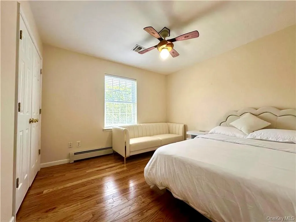 Bedroom with a closet, baseboard heating, hardwood / wood-style floors, and a ceiling fan Bedroom with a closet, baseboard heating, hardwood / wood-style floors, and a ceiling fan