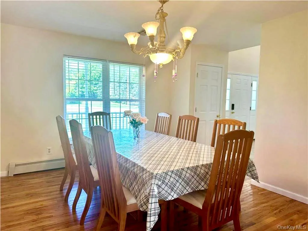 Dining room with baseboard heating, a chandelier, and light wood-style floors Dining room with baseboard heating, a chandelier, and light wood-style floors