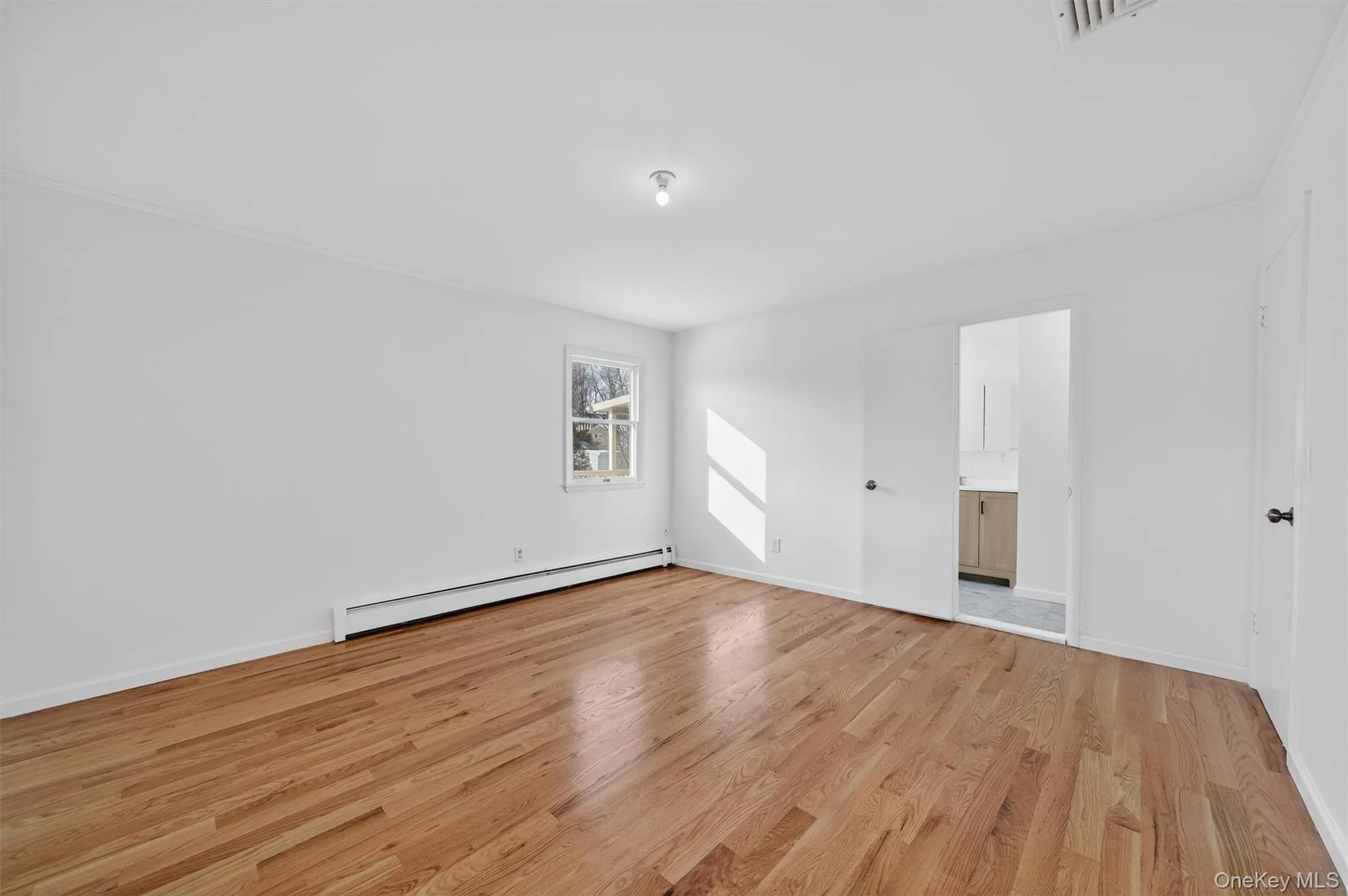 Spare room with light wood-type flooring, a baseboard heating unit, and ornamental molding Spare room with light wood-type flooring, a baseboard heating unit, and ornamental molding