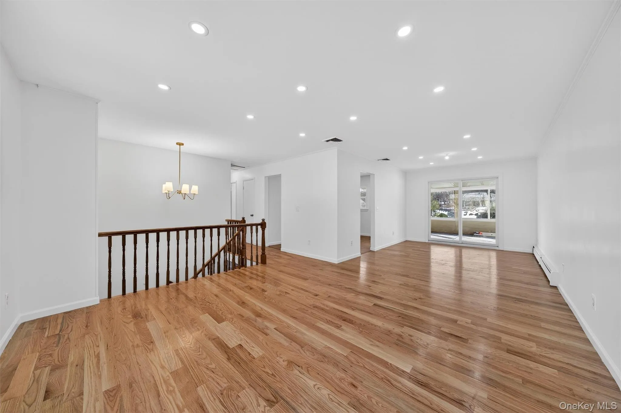 Empty room with recessed lighting, light wood-style floors, baseboard heating, and a chandelier Empty room with recessed lighting, light wood-style floors, baseboard heating, and a chandelier