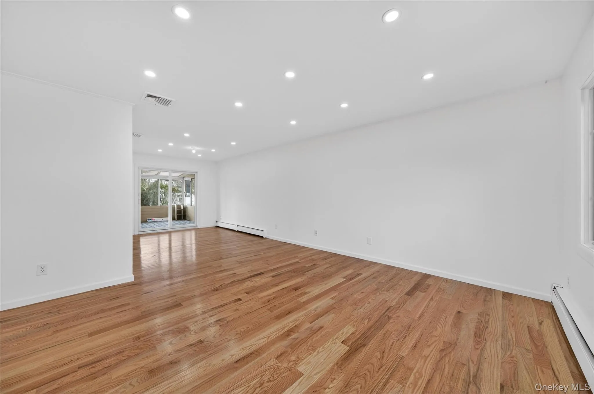 Unfurnished living room featuring recessed lighting, a baseboard radiator, and light wood-style flooring Unfurnished living room featuring recessed lighting, a baseboard radiator, and light wood-style flooring