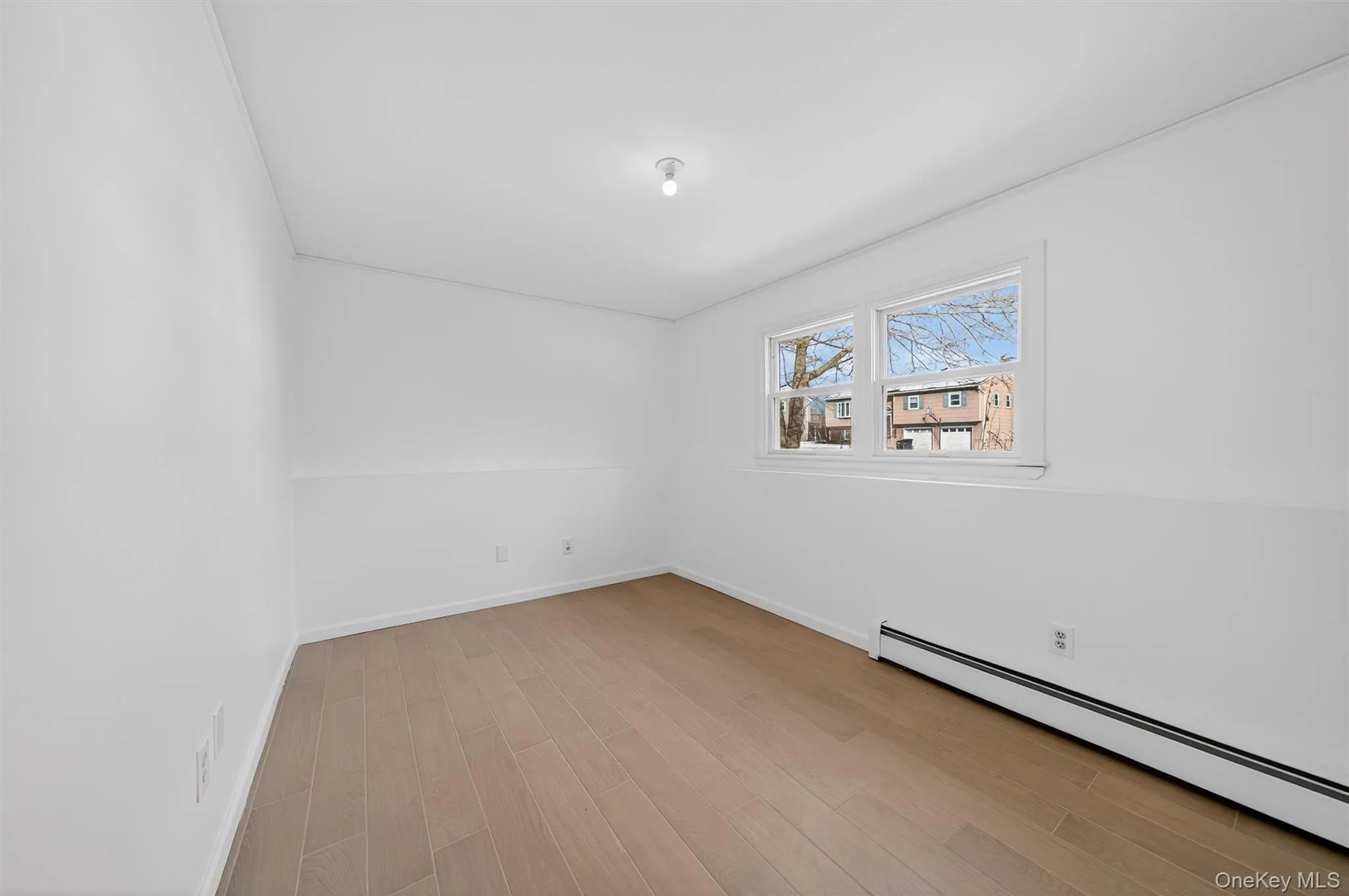 Unfurnished room featuring a baseboard radiator and light wood-style flooring Unfurnished room featuring a baseboard radiator and light wood-style flooring