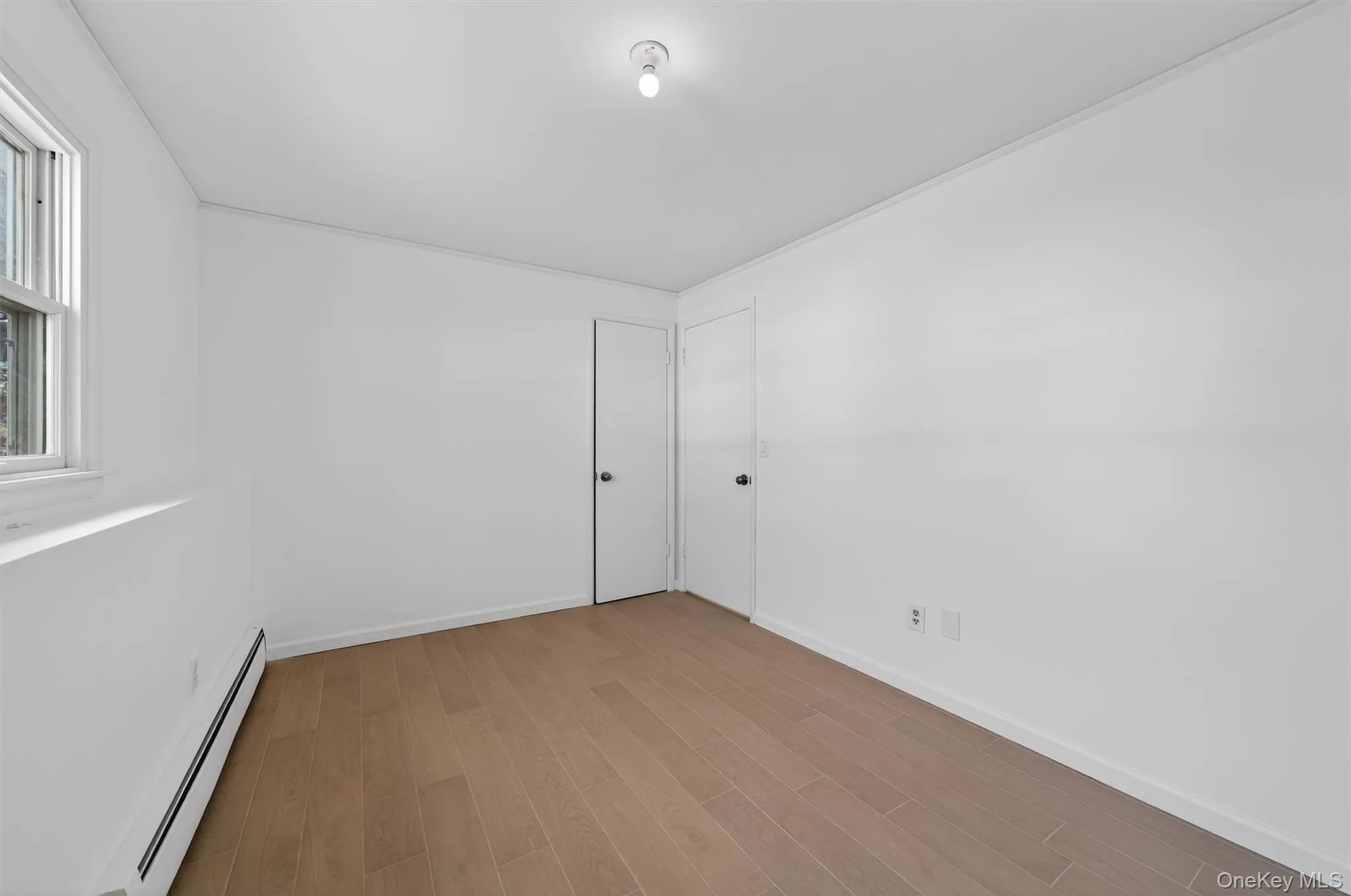 Unfurnished room with a baseboard heating unit and light wood-style floors Unfurnished room with a baseboard heating unit and light wood-style floors