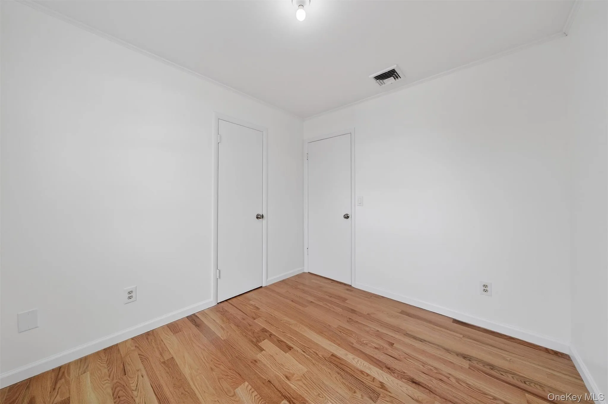 Unfurnished bedroom featuring light wood finished floors and ornamental molding Unfurnished bedroom featuring light wood finished floors and ornamental molding