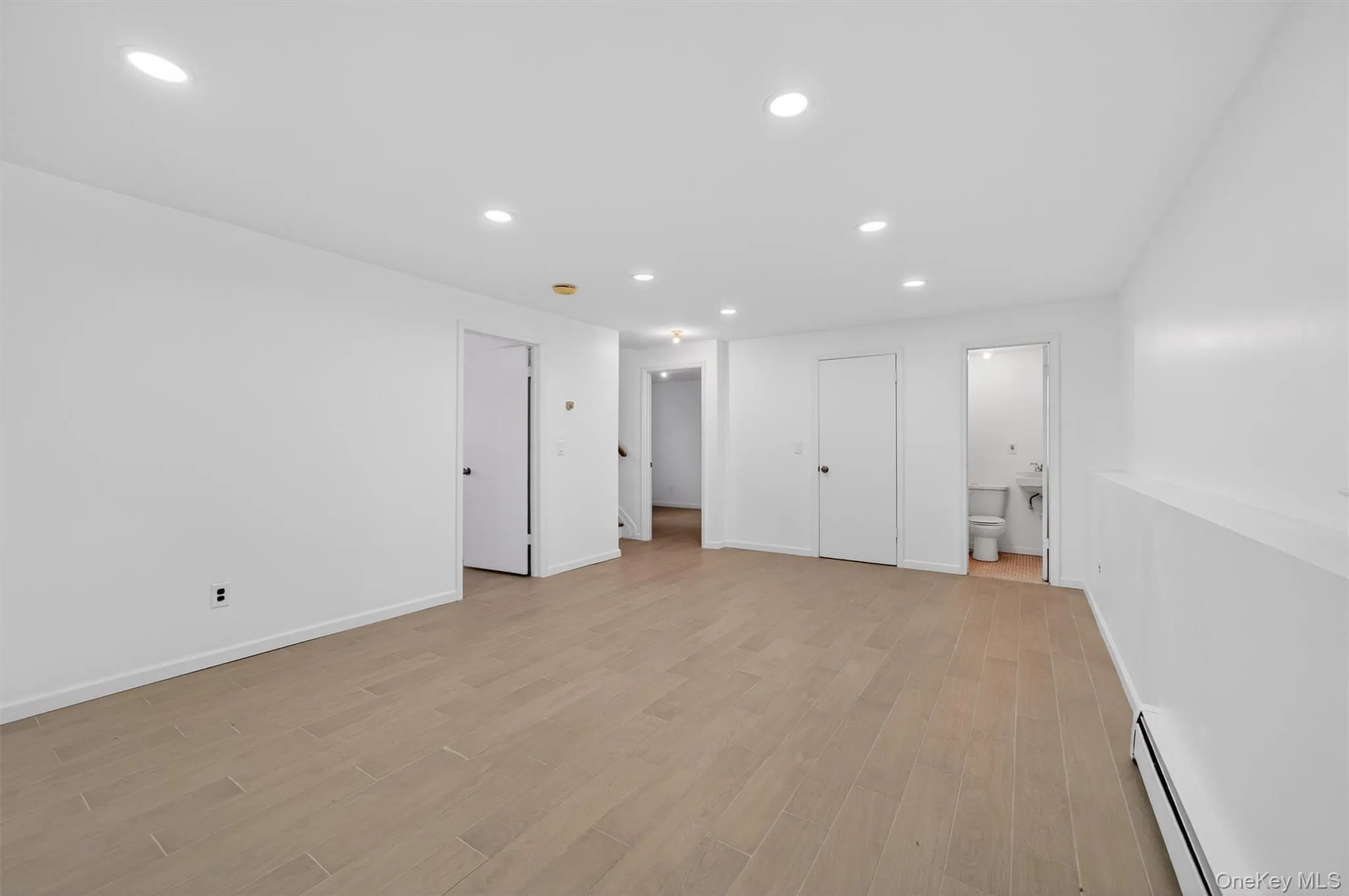 Unfurnished bedroom featuring a baseboard heating unit, recessed lighting, light wood finished floors, and connected bathroom Unfurnished bedroom featuring a baseboard heating unit, recessed lighting, light wood finished floors, and connected bathroom