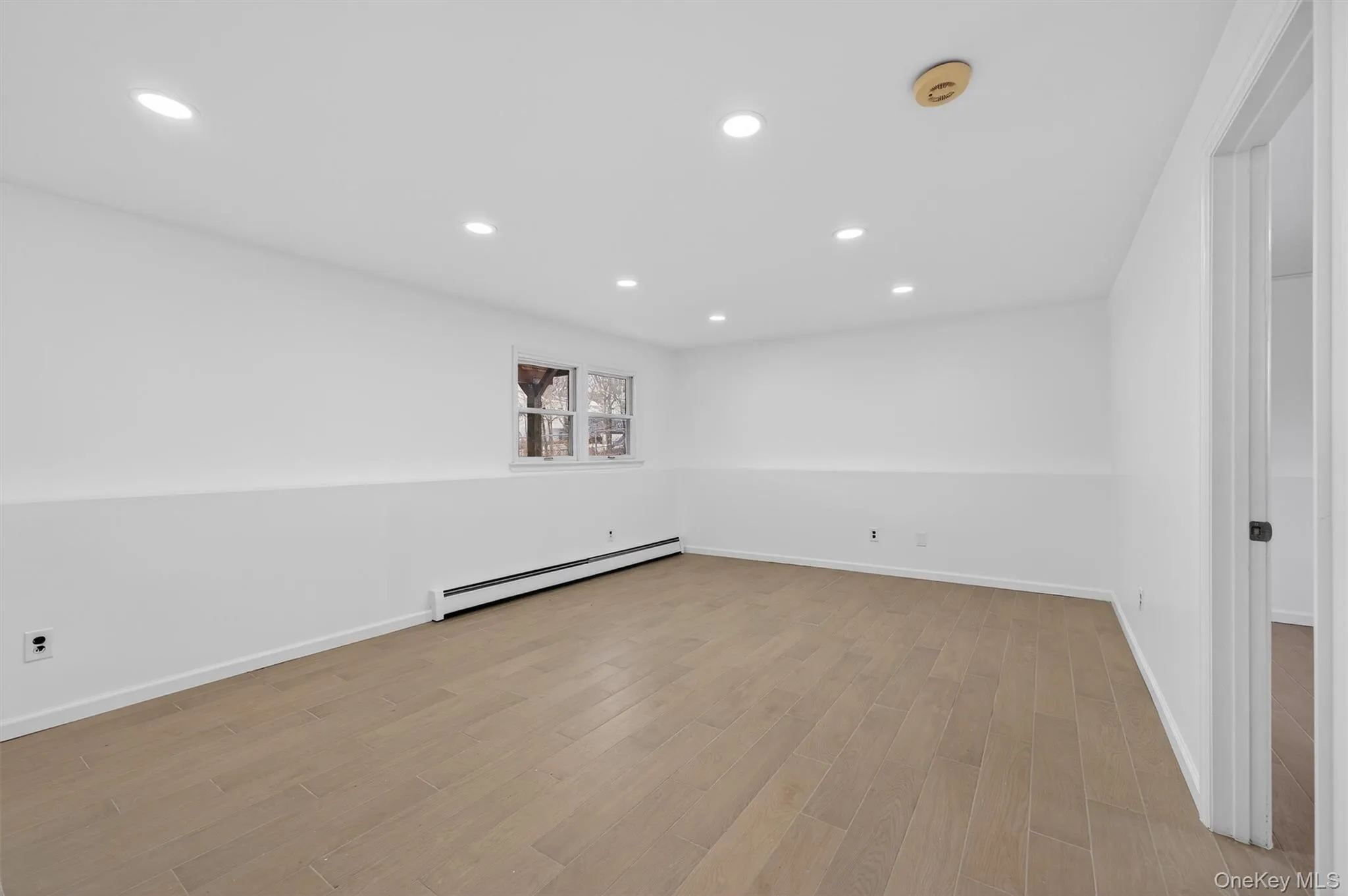 Unfurnished room with recessed lighting, a baseboard radiator, and light wood-style flooring Unfurnished room with recessed lighting, a baseboard radiator, and light wood-style flooring