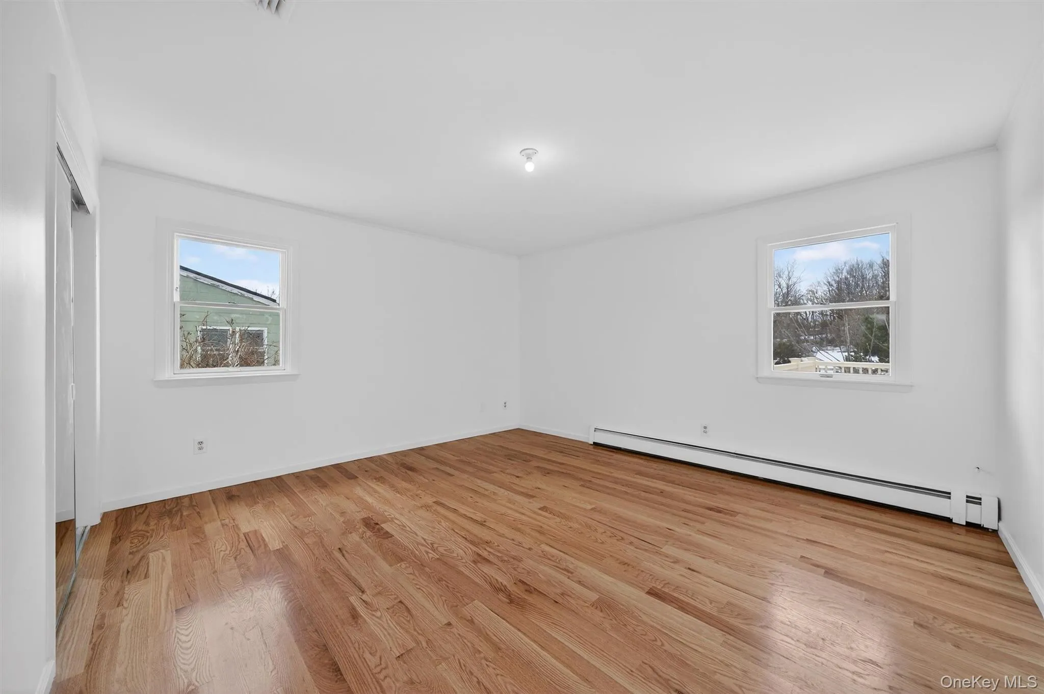 Spare room with a baseboard heating unit and light wood-type flooring Spare room with a baseboard heating unit and light wood-type flooring