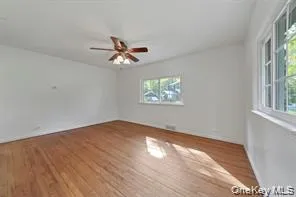 Empty room with wood finished floors and a ceiling fan Empty room with wood finished floors and a ceiling fan