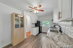 Kitchen with dark wood-style floors, light stone countertops, white cabinetry, ceiling fan, and freestanding refrigerator Kitchen with dark wood-style floors, light stone countertops, white cabinetry, ceiling fan, and freestanding refrigerator