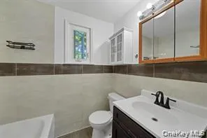 Bathroom with vanity, a bath, and tile walls Bathroom with vanity, a bath, and tile walls