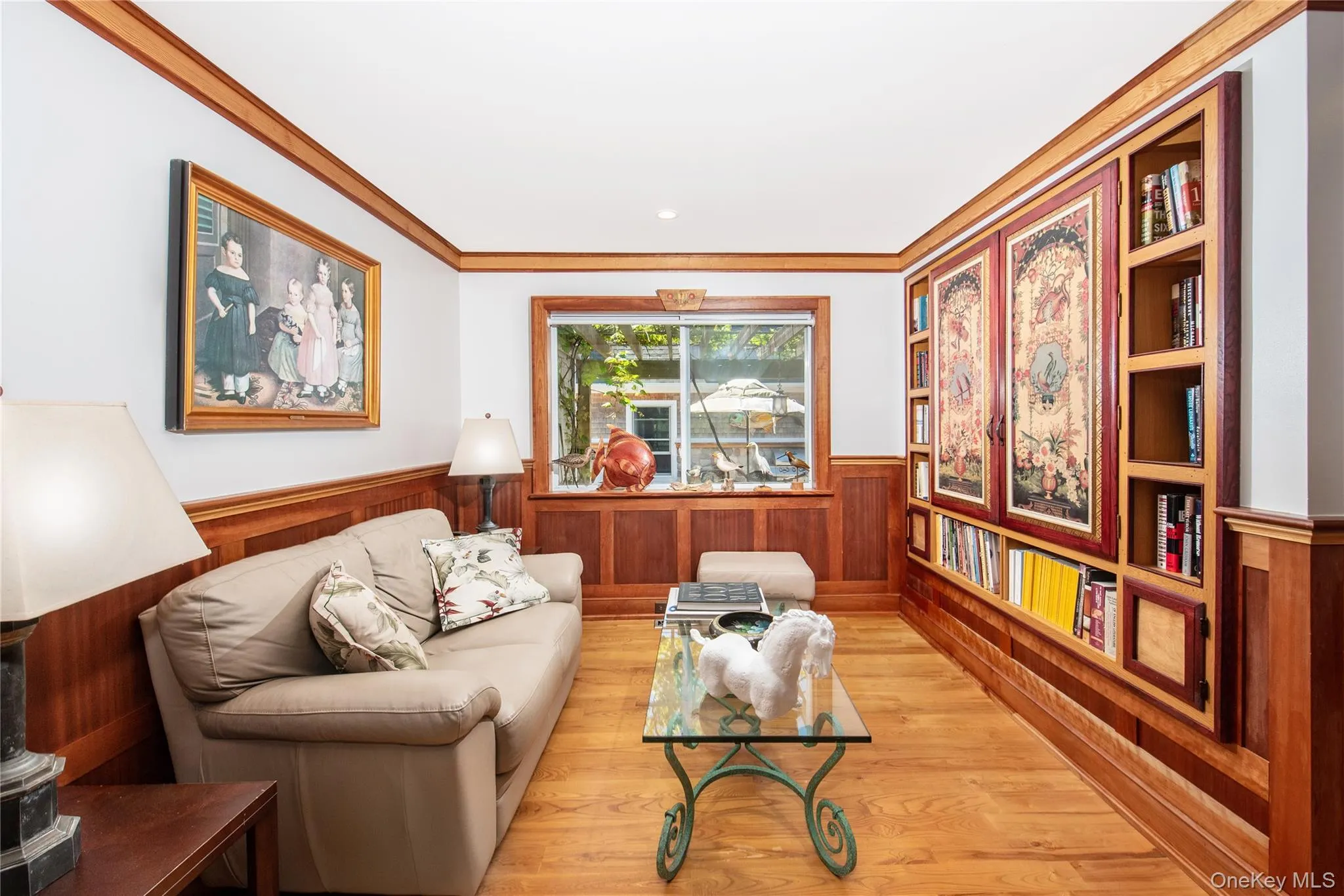 Living area with wainscoting, ornamental molding, wood finished floors, and wood walls Living area with wainscoting, ornamental molding, wood finished floors, and wood walls