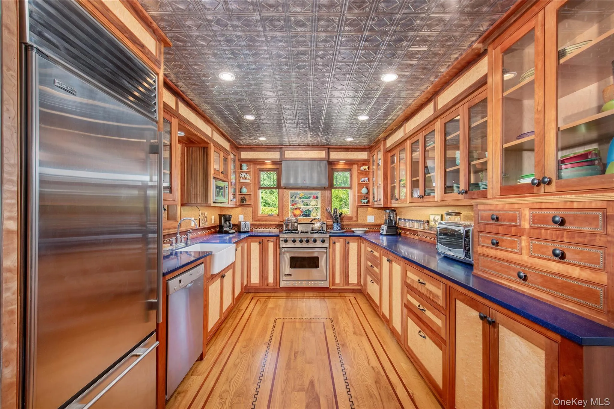 Kitchen featuring premium appliances, glass insert cabinets, recessed lighting, light wood-type flooring, and an ornate ceiling Kitchen featuring premium appliances, glass insert cabinets, recessed lighting, light wood-type flooring, and an ornate ceiling