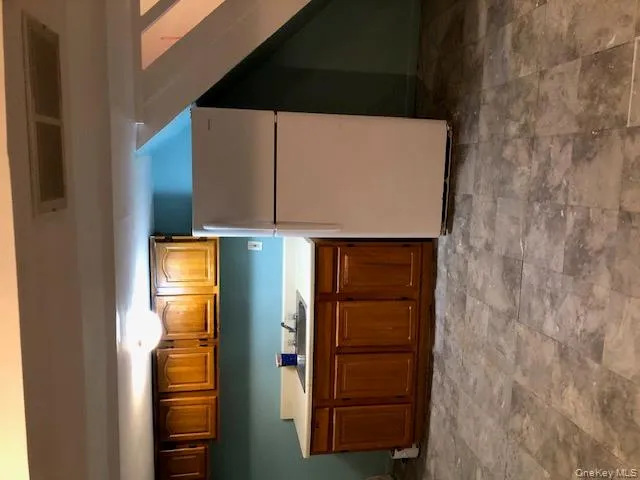 Kitchen featuring white fridge, light countertops, and brown cabinetry Kitchen featuring white fridge, light countertops, and brown cabinetry