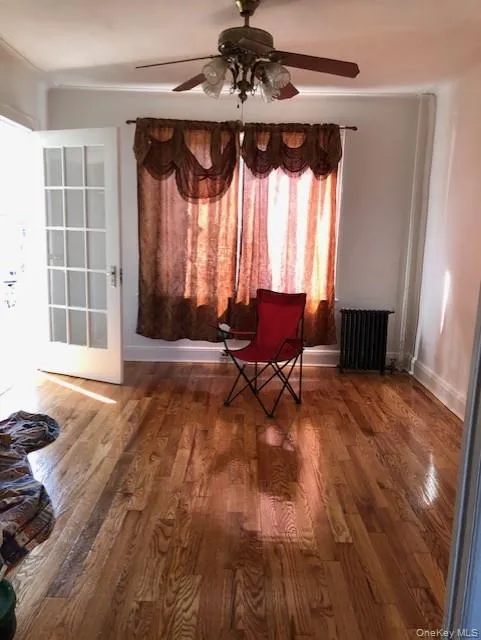 Sitting room with ceiling fan, radiator, and dark wood-type flooring Sitting room with ceiling fan, radiator, and dark wood-type flooring