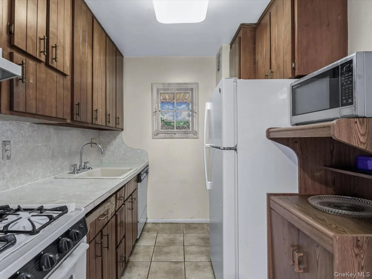 Kitchen featuring white appliances, light tile patterned floors, light countertops, and decorative backsplash Kitchen featuring white appliances, light tile patterned floors, light countertops, and decorative backsplash