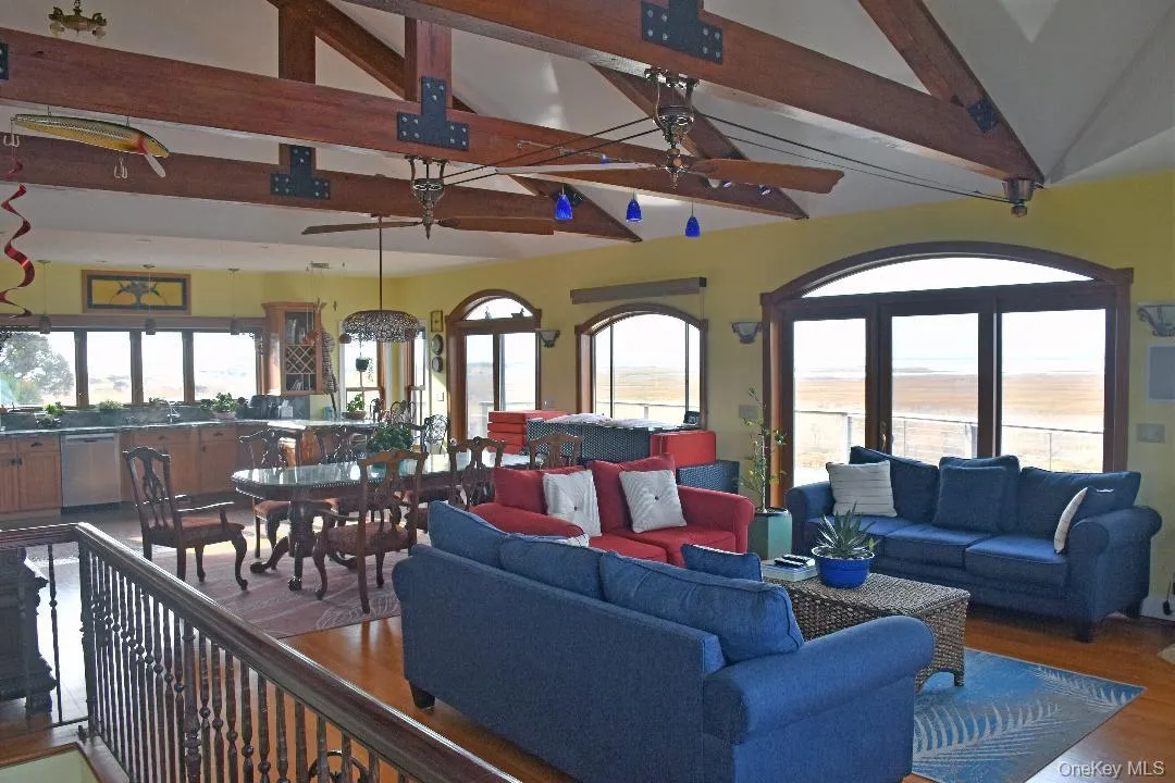 Living area featuring beamed ceiling, a ceiling fan, wood finished floors, and high vaulted ceiling Living area featuring beamed ceiling, a ceiling fan, wood finished floors, and high vaulted ceiling