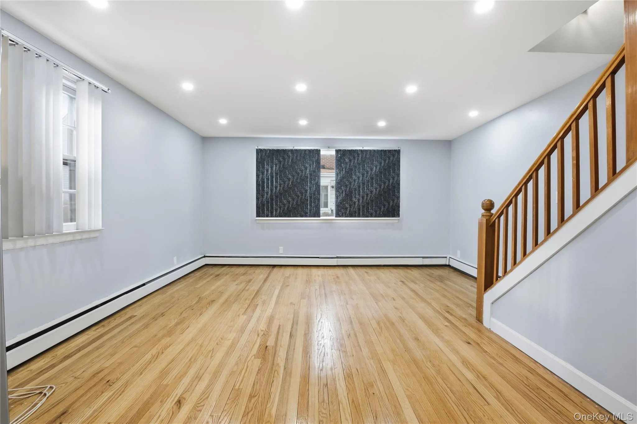Spare room with stairs, a baseboard heating unit, recessed lighting, and light wood-style flooring Spare room with stairs, a baseboard heating unit, recessed lighting, and light wood-style flooring