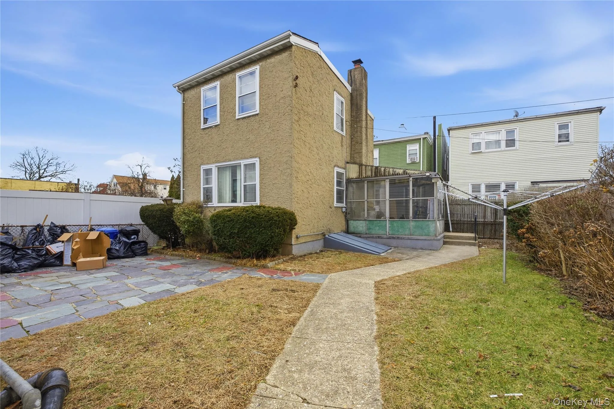 Back of house featuring a fenced backyard, a sunroom, stucco siding, and a chimney Back of house featuring a fenced backyard, a sunroom, stucco siding, and a chimney