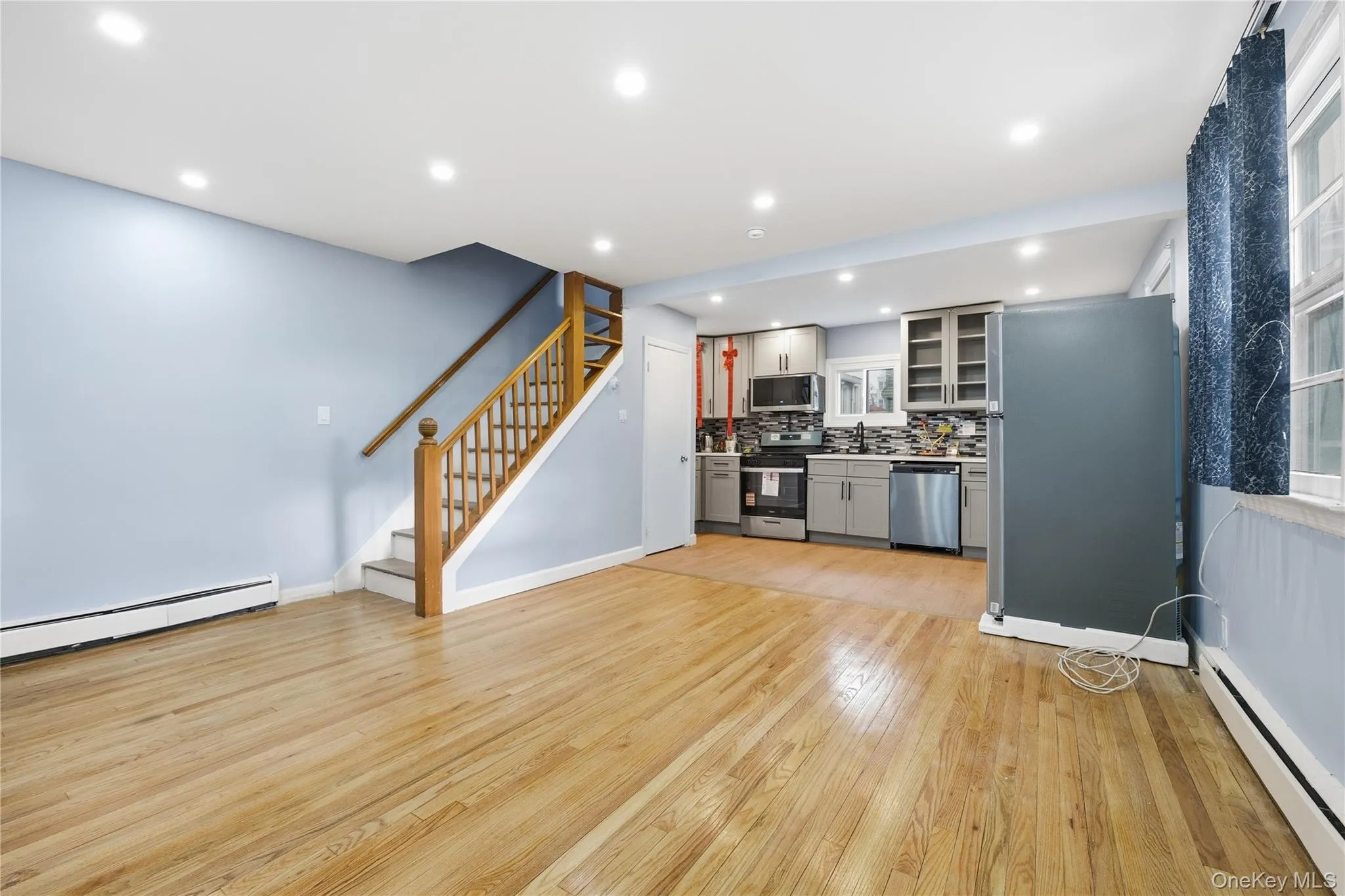 Kitchen with gray cabinets, recessed lighting, a baseboard radiator, stainless steel appliances, and decorative backsplash Kitchen with gray cabinets, recessed lighting, a baseboard radiator, stainless steel appliances, and decorative backsplash